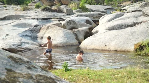 Two children bathing in a natural pool in summer Stock Footage 277101319