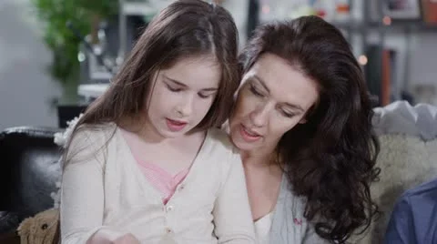 Two children being taught to read by their parents Stock Footage 12522878