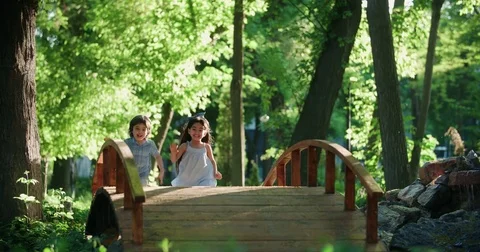 Two children,a boy and a girl running in the Park, laughing happily ,slow motion Stock Footage
