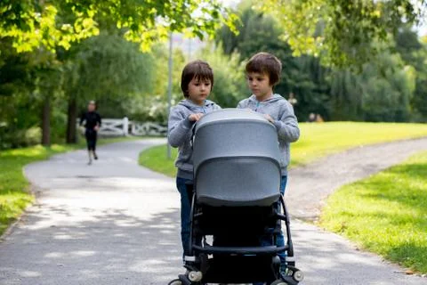 Two children, boys, pushing stroller with little baby Stock Photos
