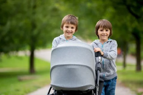 Two children, boys, pushing stroller with little baby Stock Photos