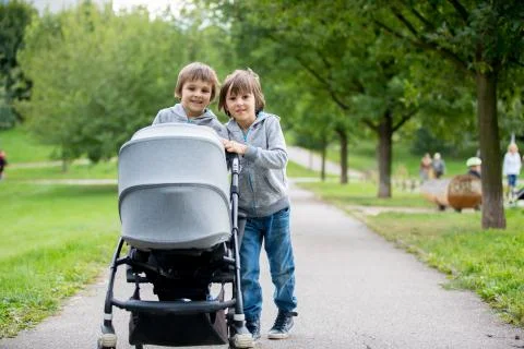 Two children, boys, pushing stroller with little baby Stock Photos