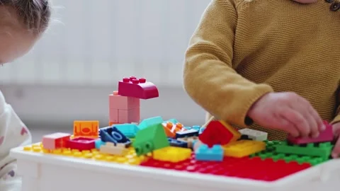 Two children build something using colorful blocks on a table. They focus on Video stock 336460263