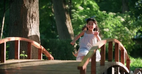 Two children,a Caucasian boy and Asian girl running in the Park ,slow motion Stock Footage