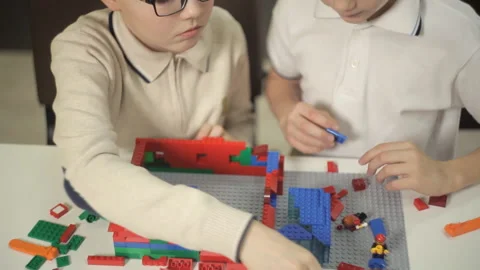 Two children, developing, build from the plastic constructor of the building Stock Footage 87958180