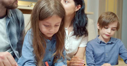 Two children drawing with colored pencils while parents discussing something Stock Footage 131664231