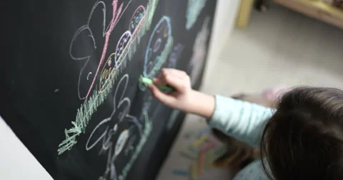 Two Children Drawing Easter Designs on Chalkboard Together Stock Footage 297699788