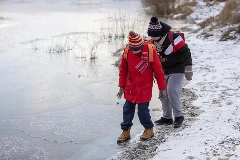 Two children dressed in bright winter clothes explore a snowy path near a f.. Foto stock