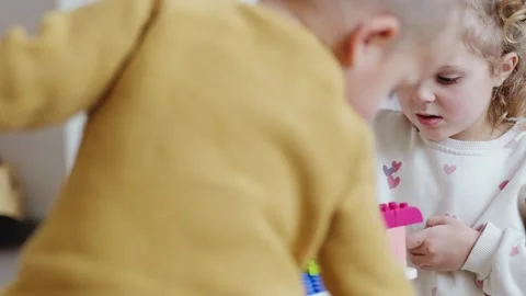 Two children engage with bright building blocks inside their home. They build Video stock 336460271
