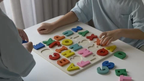 Two children engaged in playful learning, assembling colorful alphabet puzzle Stock Footage 318294517