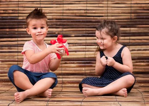 Two children examine the gift box. the boy is holding the box and the girl is Stock Photos