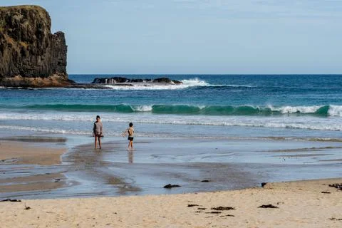 Two children explore the clear shallow waters of Bushranger Bay, framed by .. Stock Photos