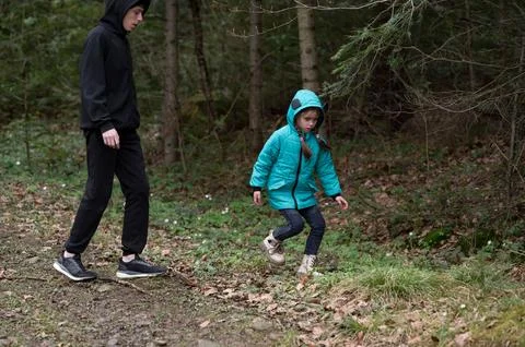 Two children explore a forest trail on a calm autumn day, sharing laughter .. Stock-Fotos
