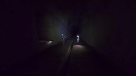 Two children exploring an abandoned underground tunnel with headlamps, walking t Vidéo 326047504