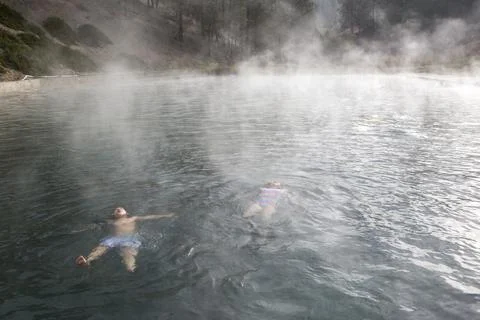 Two children float in a Trinity Hot Springs pool with steam rising Stock Photos