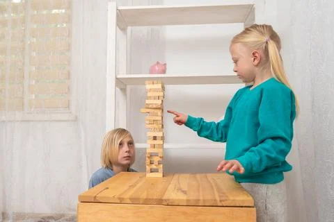 Two children focused on a stacking block game, a blonde girl pointing at th.. Stock Photos