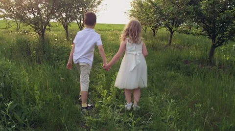 Two children hands running in a spring garden into the sunset.. Slow motion Stock Footage 50381450