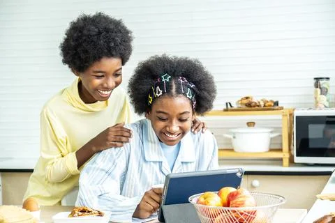 Two children happy in the kitchen while having breakfast and send a message Stock Photos