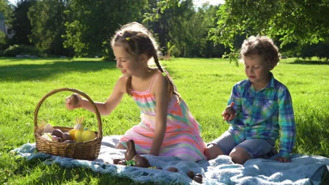 Two children having fun and eating chocolate easter eggs in garden Stock Footage 146099568