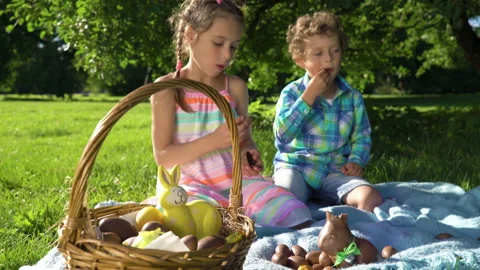 Two children having fun and eating chocolate easter eggs in garden Stock Footage 146099587