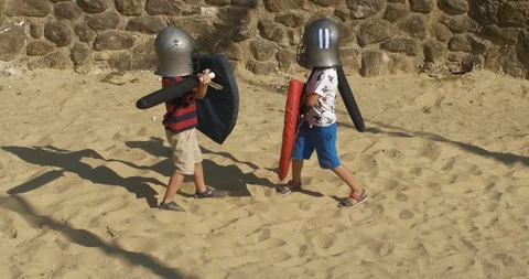 Two children in helmets with shields fight with soft swords Stock Footage 96814236