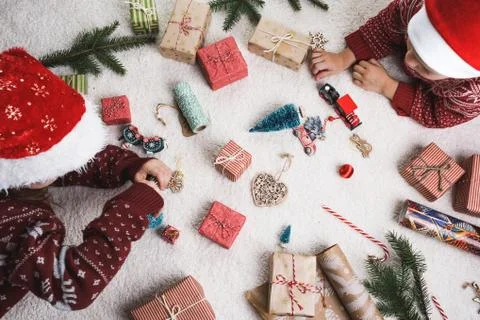 Two children at home on the carpet lay out Christmas gifts. Stock Photos
