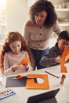 Two Children At Home With Mother Having Fun Making Craft Together Stock Photos