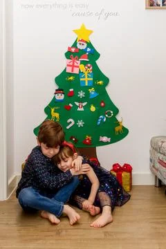 Two children hugging in the floor in front of a Christmas tree Stock Photos