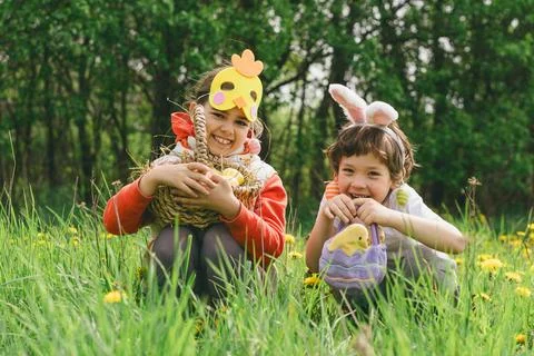 Two children hunt for Easter eggs in a spring garden. Easter tradition Stock Photos