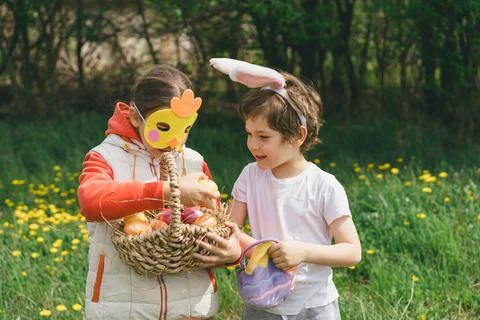 Two children hunt for Easter eggs in a spring garden. Easter tradition 스톡 사진