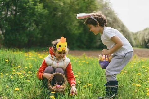 Two children hunt for Easter eggs in a spring garden. Easter tradition Stock Photos