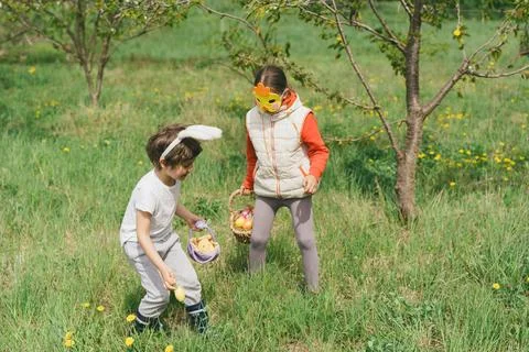 Two children hunt for Easter eggs in a spring garden. Easter tradition Stock Photos