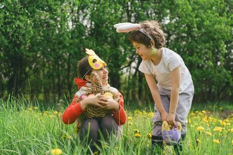 Two children hunt for Easter eggs in a spring garden. Easter tradition Stock Photos