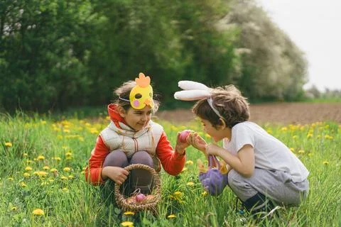 Two children hunt for Easter eggs in a spring garden. Easter tradition Stock Photos