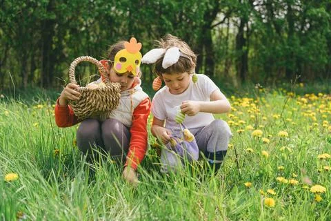Two children hunt for Easter eggs in a spring garden. Easter tradition Stock Photos