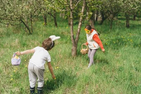 Two children hunt for Easter eggs in a spring garden. Easter tradition Stock Photos