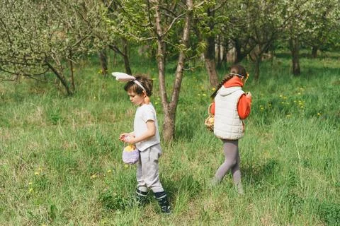 Two children hunt for Easter eggs in a spring garden. Easter tradition Stock Photos