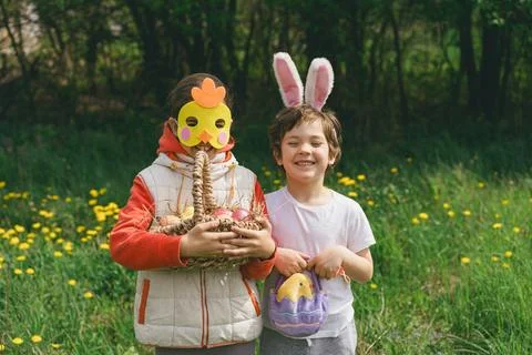 Two children hunt for Easter eggs in a spring garden. Easter tradition Stock Photos