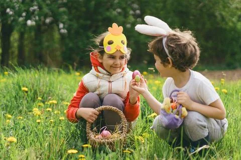 Two children hunt for Easter eggs in a spring garden. Easter tradition Stock Photos