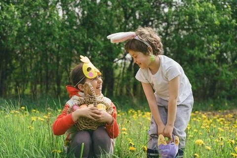 Two children hunt for Easter eggs in a spring garden. Easter tradition Stock Photos