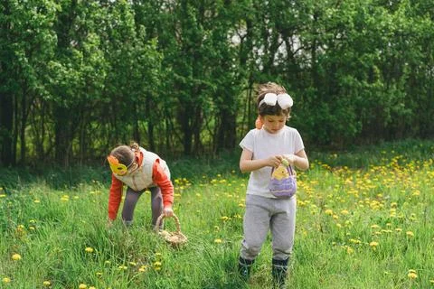 Two children hunt for Easter eggs in a spring garden. Easter tradition Foto stock