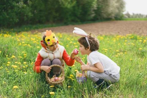 Two children hunt for Easter eggs in a spring garden. Easter tradition Stock Photos