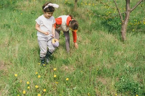 Two children hunt for Easter eggs in a spring garden. Easter tradition Stock Photos