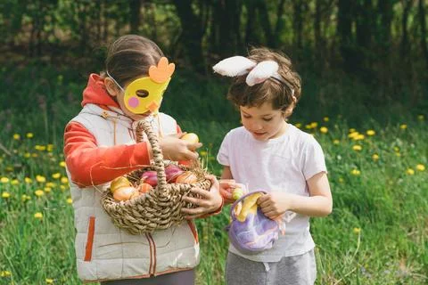 Two children hunt for Easter eggs in a spring garden. Easter tradition Stock Photos