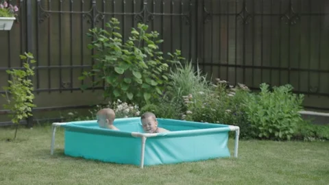 Two children joyously splashing in inflatable pool embodying essence of happy Stock Footage 279566047