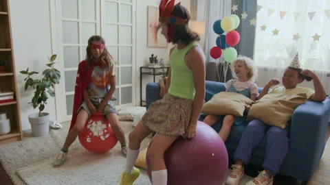 Two Children Jumping on Hopper Balls, Three Kids Encouraging Them at Party Stock Footage 295282579