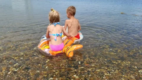 Two children on laps in the sea Stock Footage 157524506