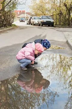 Two children look in a puddle Stock Photos