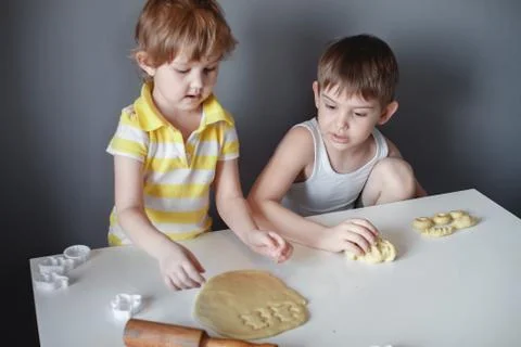 Two children make cookie mould on a white table. Preparation of homemade dess Stock Photos