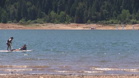 Two  children on a paddle board glide across the water Video stock 52319160